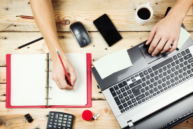 電卓とパソコンとメモをとる人