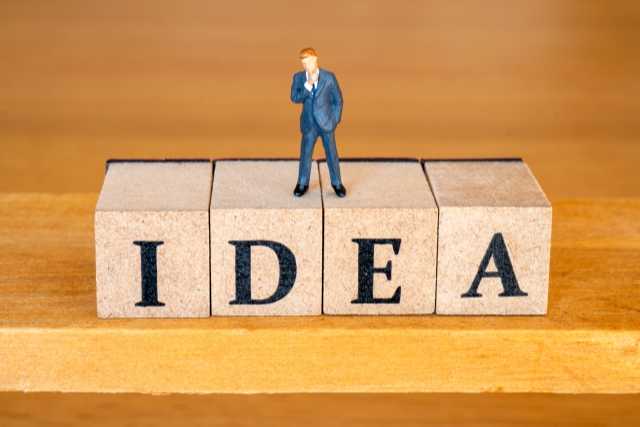 ideaと書かれている積み木の上に立つ男性の置物