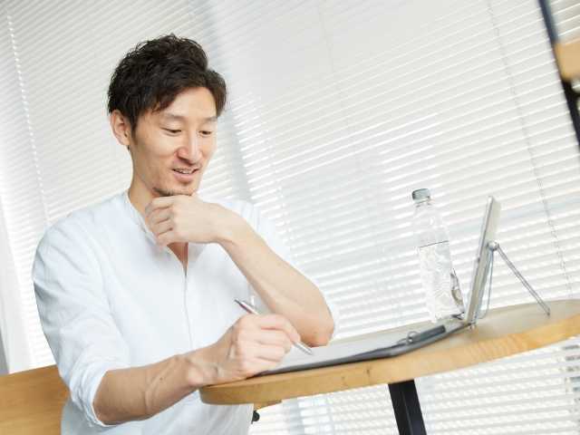 紙に何かを書く男性