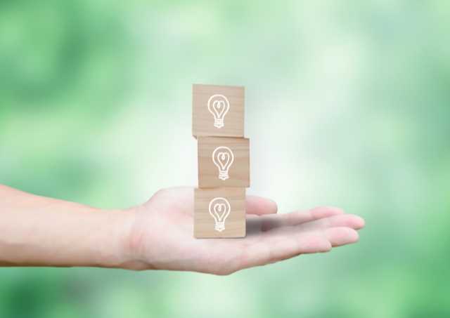 ３つの電球が書かれた積み木を持つ手