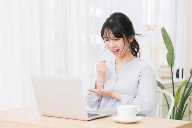 パソコンの前で嬉しそうに笑う女性